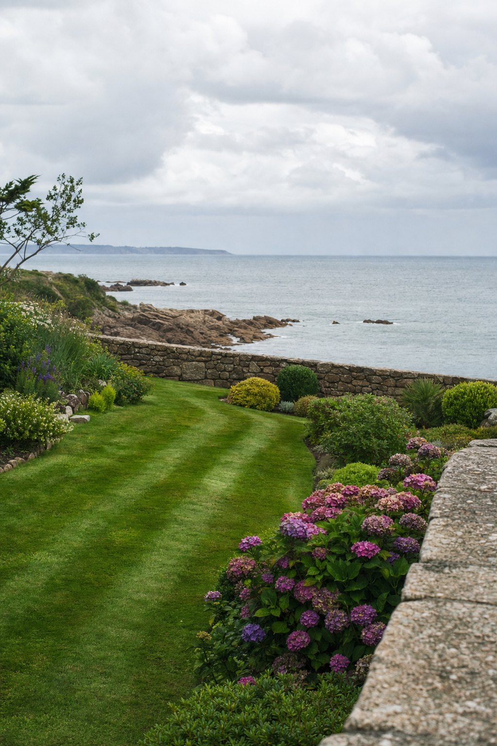 Un jardin de bord de mer breton entretenu, pelouse tondue, hortensias et muret de granit
