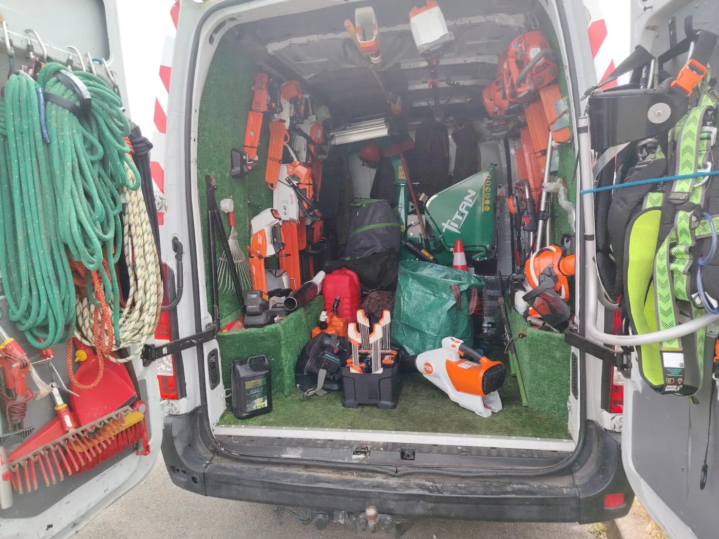 L'arrière du camion ouvert, cordes, tronçonneuses et casques rangés